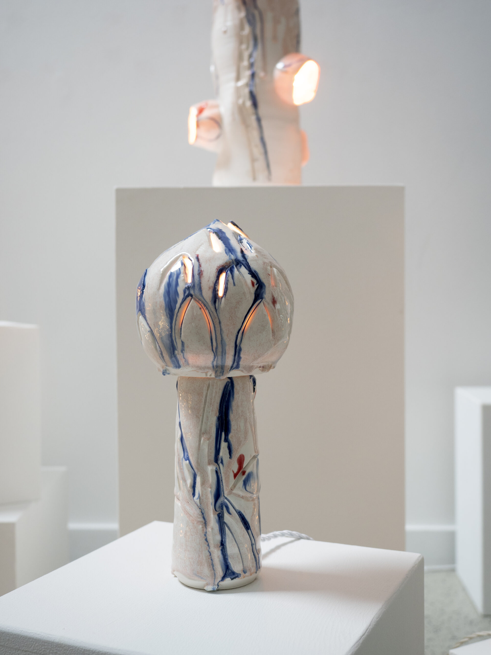 Porcelain light sculpture composed of two stacked organic forms with carved details and subtle color accents, suggesting a flower about to bloom.