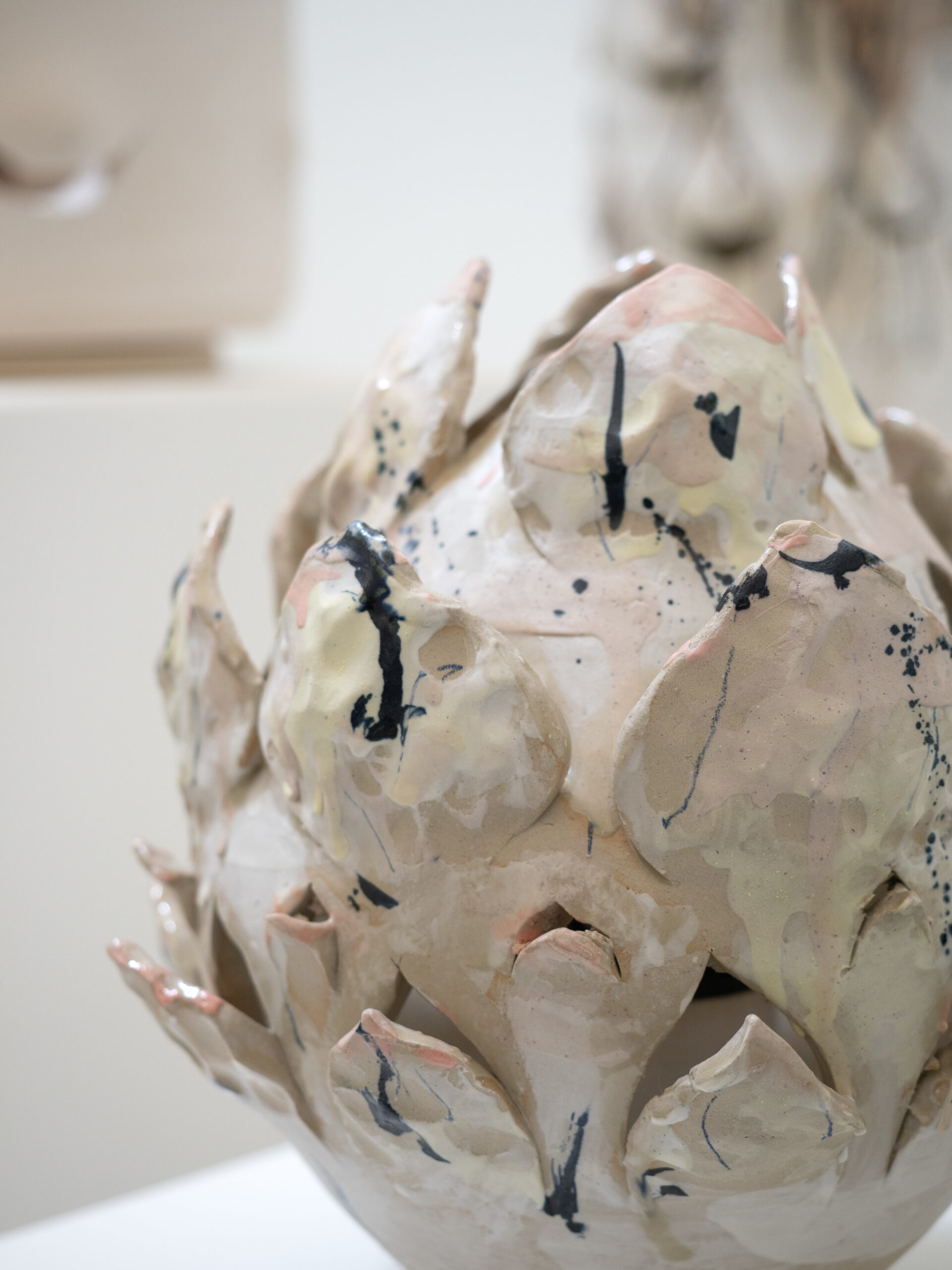 High-fired stoneware light sculpture inspired by an opening flower, with subtle porcelain details, carved textures, and soft blue, yellow, and pink accents.